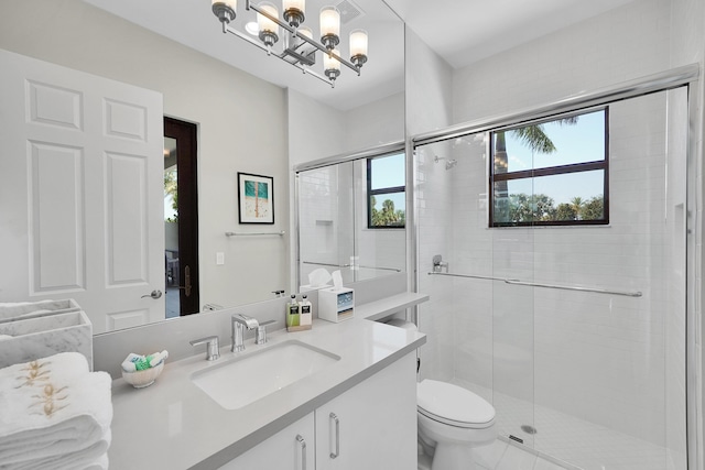 bathroom with a chandelier, a shower stall, vanity, and toilet