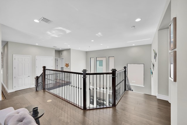corridor with an upstairs landing, wood finished floors, recessed lighting, and baseboards