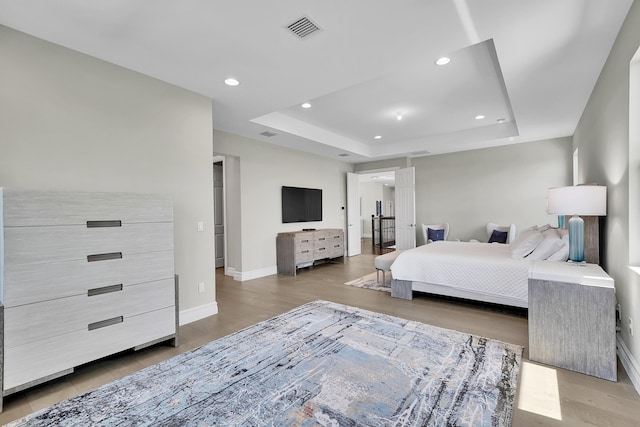 bedroom with baseboards, a raised ceiling, light wood-type flooring, and recessed lighting