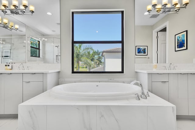 bathroom featuring a chandelier, a marble finish shower, a bath, and two vanities