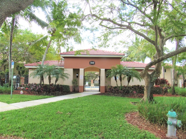 3810 N Jog Rd Unit 204, West Palm Beach, FL 33411 - view of front of property with stucco siding, a front lawn, a tile roof, and a gate
