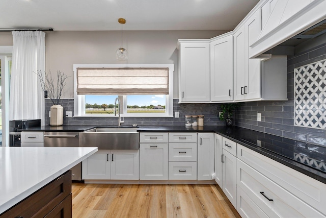 18102 Bridle Way, Port Saint Lucie, FL 34987 - kitchen with a sink, premium range hood, white cabinets, decorative backsplash, and light wood-style flooring