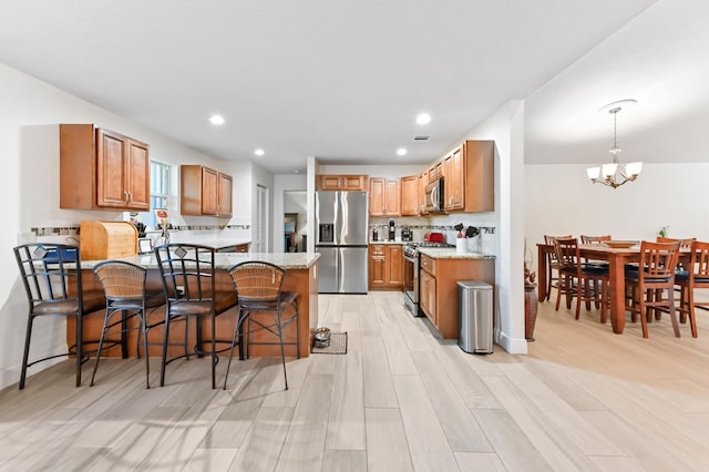 1184 Landings Run, Greenacres, FL 33413 - kitchen with stainless steel appliances, a chandelier, a peninsula, light stone countertops, and a kitchen breakfast bar