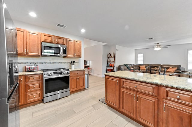1184 Landings Run, Greenacres, FL 33413 - kitchen featuring appliances with stainless steel finishes, open floor plan, brown cabinetry, ceiling fan, and healthy amount of natural light