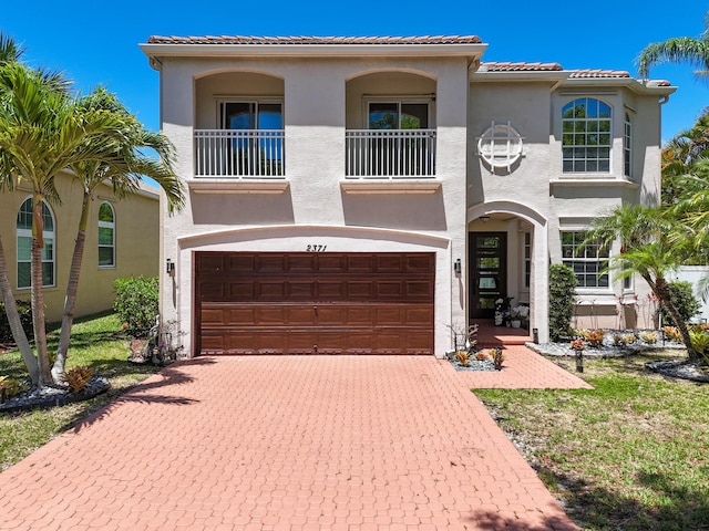 2371 Simonson Dr, Wellington, FL 33414 - mediterranean / spanish-style home featuring a balcony, an attached garage, stucco siding, and decorative driveway