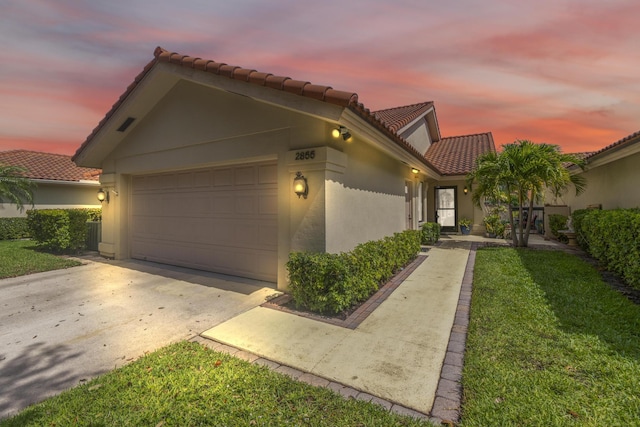 2855 Eagle Ln, West Palm Beach, FL 33409 - mediterranean / spanish home with a tile roof, stucco siding, driveway, an attached garage, and a lawn