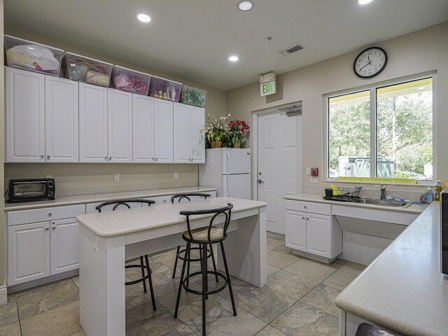 5151 Formosa Cir, Vero Beach, FL 32967 - kitchen featuring freestanding refrigerator, recessed lighting, white cabinetry, light countertops, and a kitchen bar