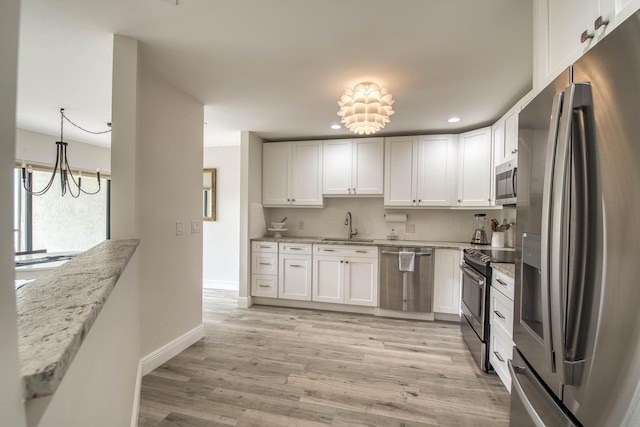 6 E Lexington Ln Unit C, Palm Beach Gardens, FL 33418 - kitchen with stainless steel appliances, a sink, a chandelier, tasteful backsplash, and white cabinetry