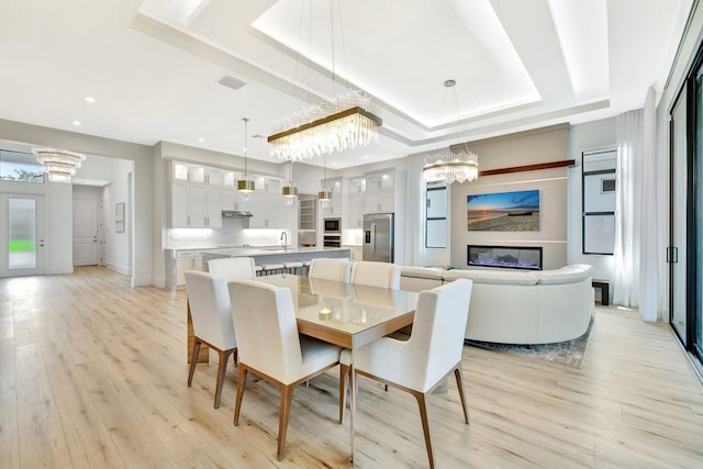 17135 SW Ambrose Way, Port Saint Lucie, FL 34986 - dining space with a tray ceiling, a chandelier, light wood-style flooring, and recessed lighting