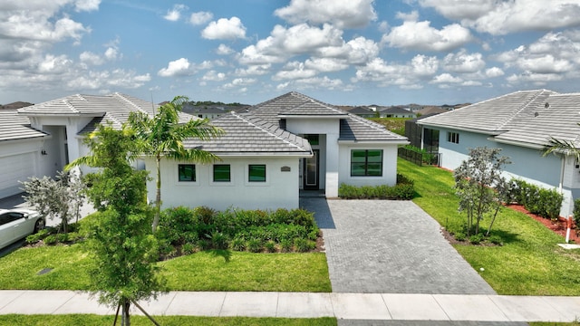 17135 SW Ambrose Way, Port Saint Lucie, FL 34986 - contemporary home featuring stucco siding, a front lawn, a residential view, a tiled roof, and driveway