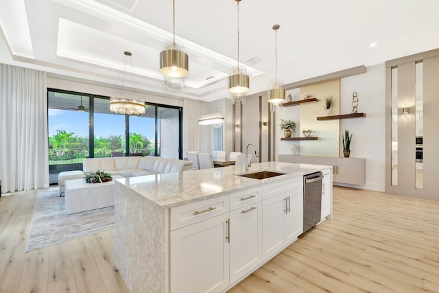 17135 SW Ambrose Way, Port Saint Lucie, FL 34986 - kitchen featuring a sink, dishwasher, a raised ceiling, an island with sink, and light wood finished floors