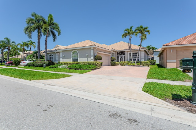 view of front of house featuring a garage, driveway, stucco siding, a tiled roof, and a front lawn