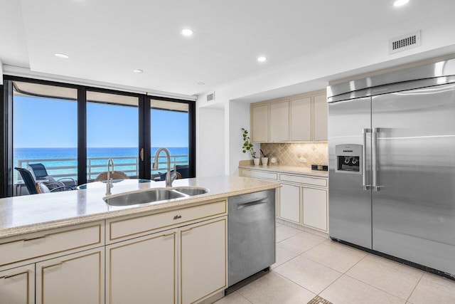 1500 S Ocean Blvd Unit 804, Boca Raton, FL 33432 - kitchen with stainless steel appliances, a sink, cream cabinets, decorative backsplash, and light tile patterned flooring