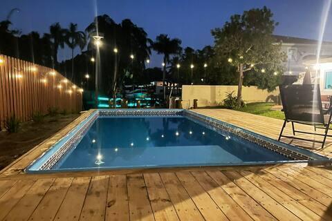 2809 SW 46th St, Dania Beach, FL 33312 - pool at night with a wooden deck and a fenced backyard