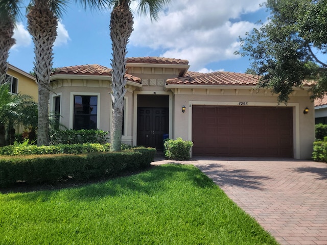 4295 55th St, Vero Beach, FL 32967 - mediterranean / spanish house featuring a garage, decorative driveway, a tiled roof, stucco siding, and a front lawn