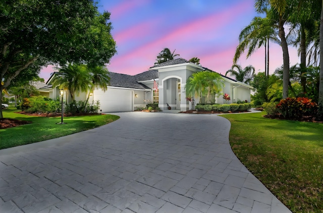 550 SW Sanctuary Dr, Port Saint Lucie, FL 34986 - view of front of home featuring curved driveway, a garage, stucco siding, and a yard