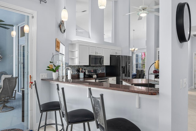 550 SW Sanctuary Dr, Port Saint Lucie, FL 34986 - kitchen featuring stainless steel electric range oven, dark countertops, refrigerator with ice dispenser, ceiling fan, and white cabinets