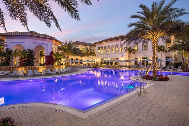 7919 L Aquila Way, Delray Beach, FL 33446 - pool at dusk featuring a community pool and a patio
