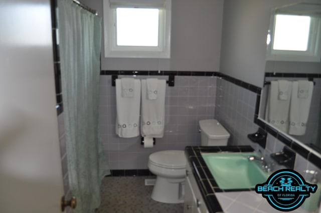 4318 7th Ave, Marianna, FL 32446 - full bathroom with toilet, vanity, plenty of natural light, a wainscoted wall, and tile walls