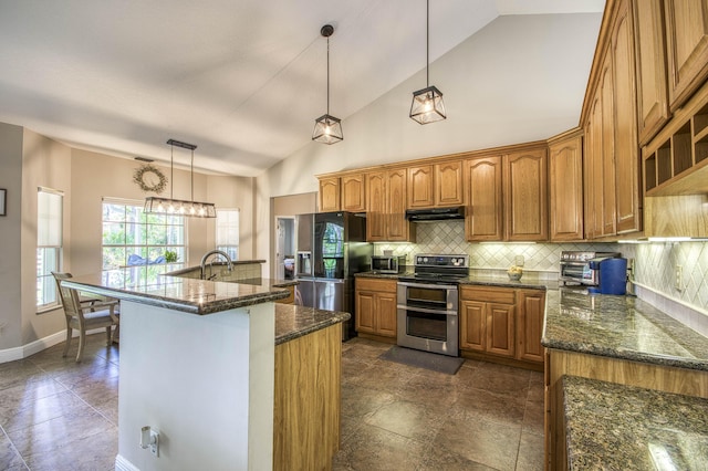 15048 85th Rd N, The Acreage, FL 33470 - kitchen featuring appliances with stainless steel finishes, under cabinet range hood, brown cabinetry, decorative backsplash, and dark stone countertops