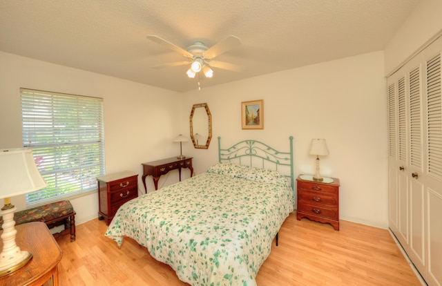 bedroom with a closet, light wood-type flooring, a ceiling fan, and a textured ceiling