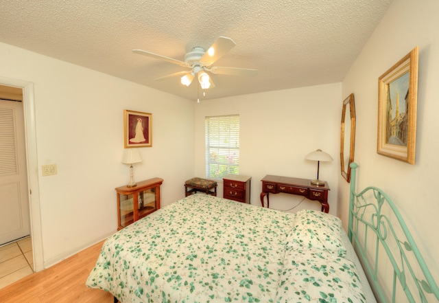 bedroom featuring light wood-type flooring, a textured ceiling, and a ceiling fan