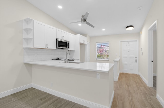 8583 Overset Ln Unit C, Boca Raton, FL 33496 - kitchen with stainless steel microwave, open shelves, a peninsula, tasteful backsplash, and light wood-style floors