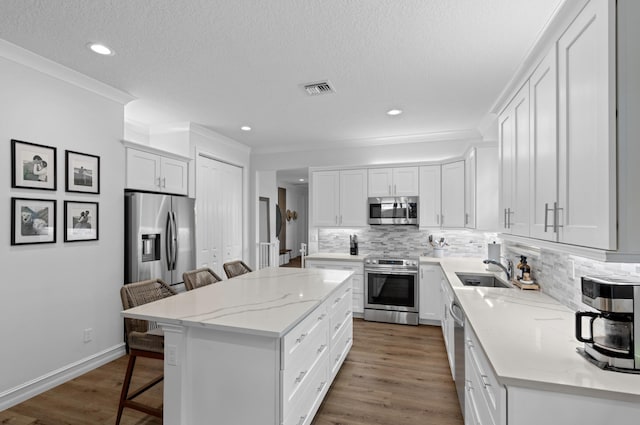 17564 Cinquez Park Rd W, Jupiter, FL 33458 - kitchen featuring stainless steel appliances, a kitchen bar, a sink, tasteful backsplash, and a kitchen island