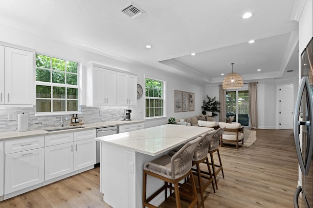 17564 Cinquez Park Rd W, Jupiter, FL 33458 - kitchen featuring a sink, a tray ceiling, light wood finished floors, decorative backsplash, and a center island