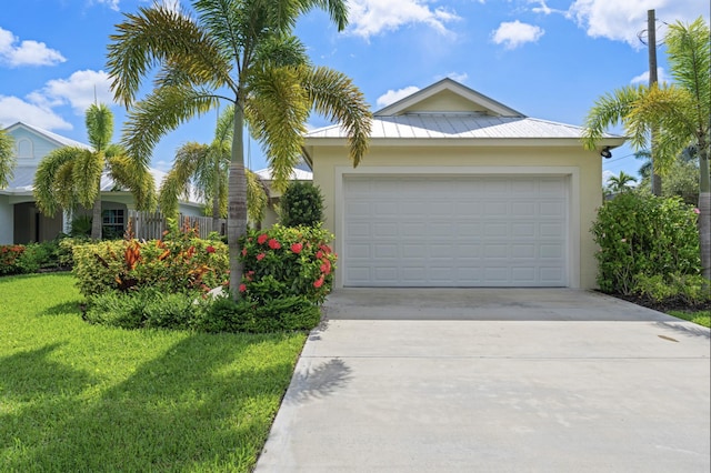 17564 Cinquez Park Rd W, Jupiter, FL 33458 - view of front of house featuring concrete driveway, a front lawn, stucco siding, metal roof, and an attached garage