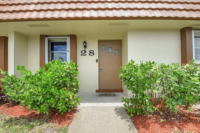5730 Fernley Dr E Unit 28, West Palm Beach, FL 33415 - view of exterior entry with stucco siding and a tiled roof