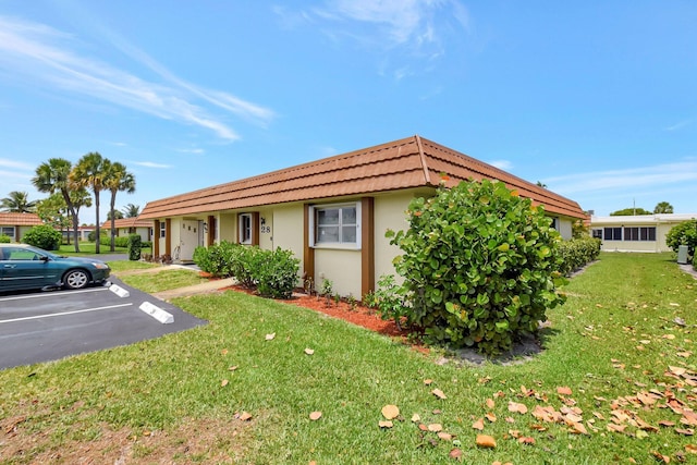 5730 Fernley Dr E Unit 28, West Palm Beach, FL 33415 - view of front facade with stucco siding, a front lawn, uncovered parking, a tiled roof, and mansard roof
