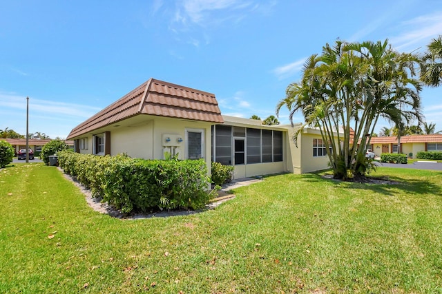 5730 Fernley Dr E Unit 28, West Palm Beach, FL 33415 - back of property with stucco siding, a sunroom, a yard, and mansard roof