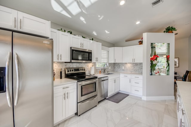 208 Legendary Cir, Palm Beach Gardens, FL 33418 - kitchen featuring appliances with stainless steel finishes, a sink, decorative backsplash, vaulted ceiling, and light countertops