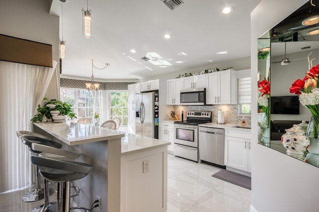 208 Legendary Cir, Palm Beach Gardens, FL 33418 - kitchen with stainless steel appliances, backsplash, white cabinets, a breakfast bar, and a peninsula