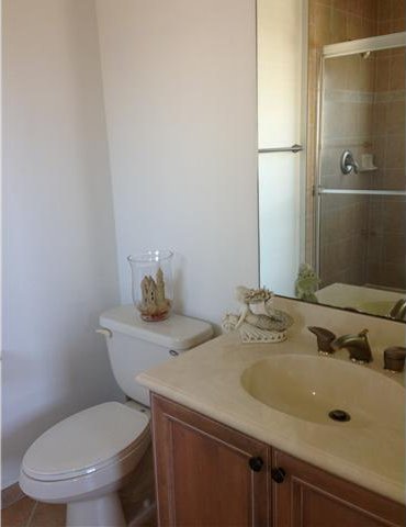 full bath featuring toilet, vanity, a tile shower, and tile patterned flooring