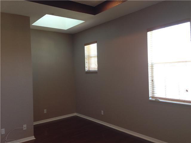 unfurnished room featuring a skylight, plenty of natural light, baseboards, and dark wood finished floors