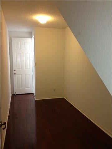 additional living space with dark wood-style floors and baseboards