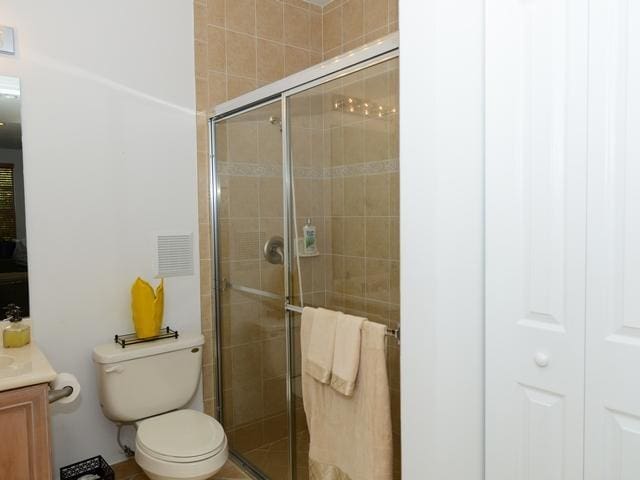 bathroom featuring a shower stall, vanity, and toilet