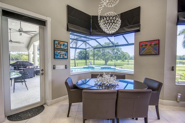 tiled dining room featuring a sunroom, a textured wall, baseboards, ceiling fan, and a chandelier