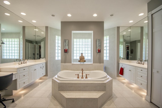 bathroom with a bath, two vanities, plenty of natural light, tile patterned flooring, and recessed lighting