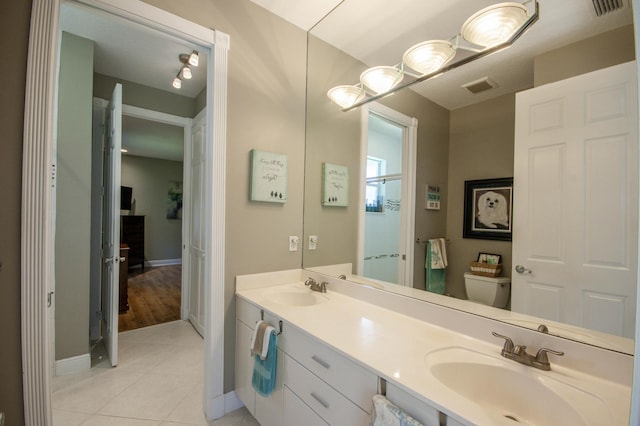 bathroom with tile patterned floors, baseboards, toilet, and double vanity