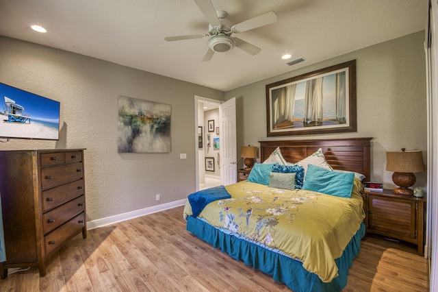 bedroom with wood finished floors, baseboards, a ceiling fan, a textured wall, and recessed lighting