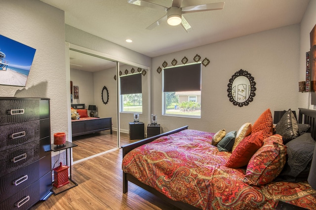 bedroom featuring wood finished floors, ceiling fan, a textured wall, and a closet