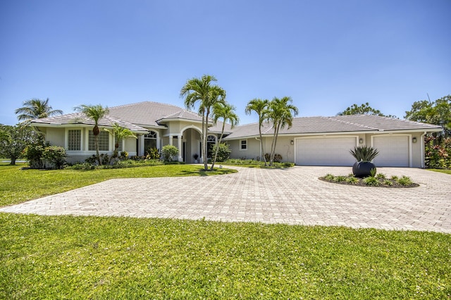 view of front of property featuring decorative driveway, stucco siding, a front yard, and an attached garage
