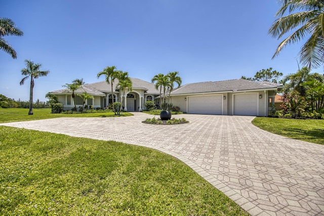 ranch-style home featuring decorative driveway, a garage, a front yard, and stucco siding