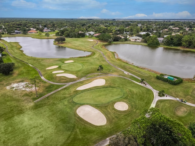 aerial overview of property's location with a large body of water, a tree filled landscape, and a local golf course