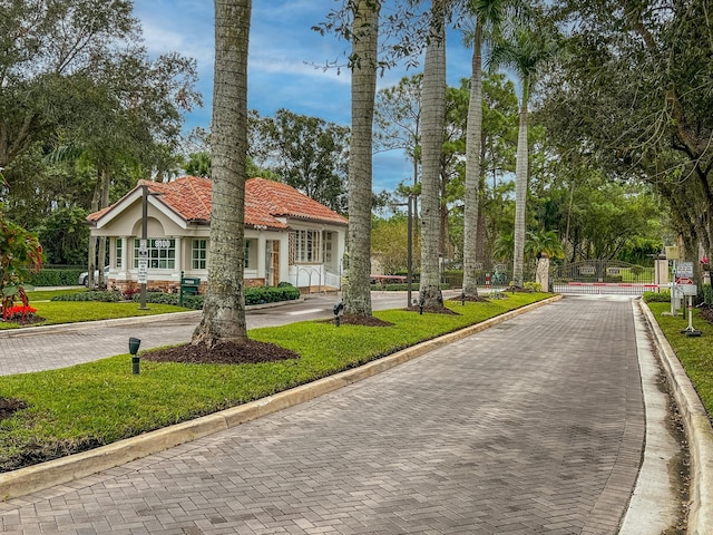 view of front of property featuring decorative driveway, a front yard, stucco siding, and a tiled roof