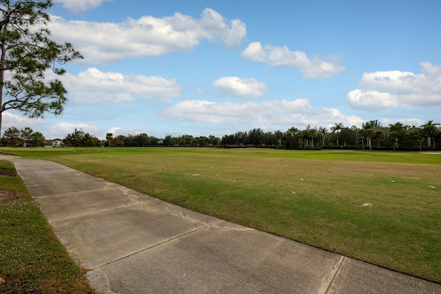 view of grassy yard with view of golf course and view of wooded area