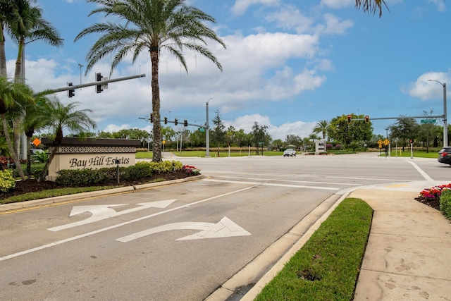 view of asphalt street with traffic lights, curbs, street lighting, traffic signs, and sidewalks